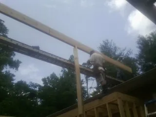 Carpenter setting a ridge beam over a new addition frame — Ice Dam Removal by Roofing Brothers in Mantoloking