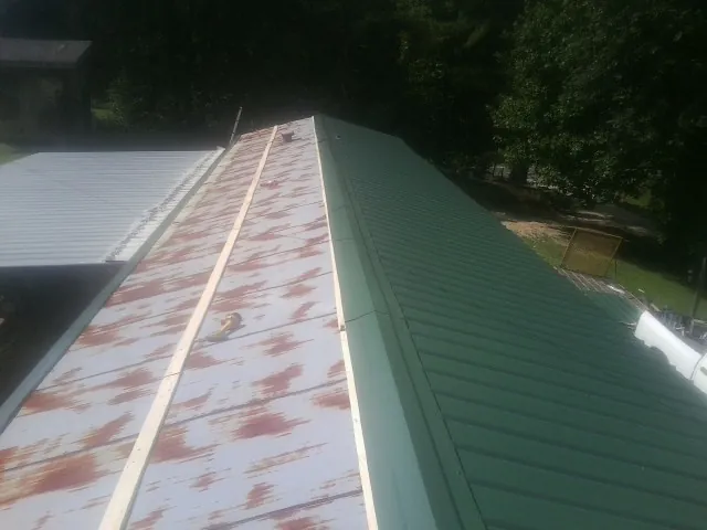 Old rusted panels beside newly installed green metal roofing — Wind Damage Roof Repair by Roofing Brothers in Mantoloking