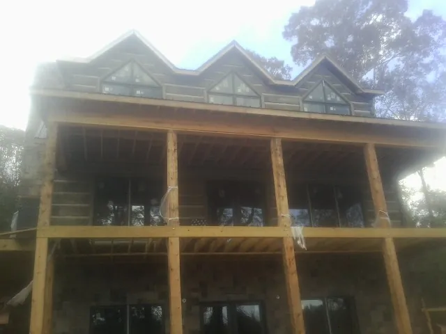 Dormers and porch framing on a large log home under construction — Roof Coating work by our crew in Mantoloking