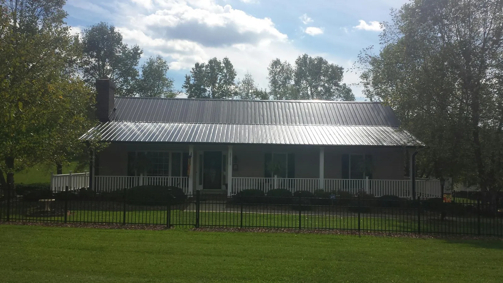 Gray metal roof on a brick ranch with a full width front porch — Gutter Guard Installation work by our crew in Mantoloking